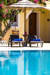 two chairs and an umbrella next to a swimming pool at Smaragdi in Perivolos