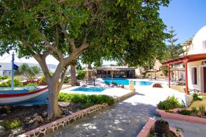a tree next to a swimming pool with a boat at Smaragdi in Perivolos