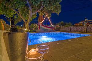 a swimming pool at night with candles and a boat at Smaragdi in Perivolos