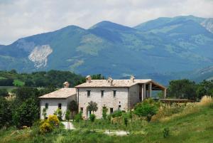 uma casa numa colina com montanhas ao fundo em Agriturismo Molleone em Cagli