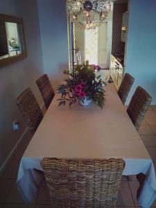 a dining room table with a vase of flowers on it at Harbour Views in Simonʼs Town