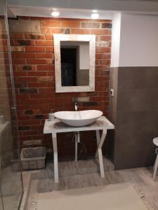 a bathroom with a white sink and a brick wall at LoftStyle Apartament in Żyrardów