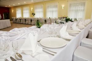 a long white table with white plates and silverware at Vistula Hotel in Świecie