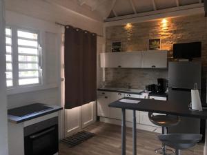 una cocina con armarios blancos y una mesa con sillas. en Gîte Akwarel en Vieux-Habitants