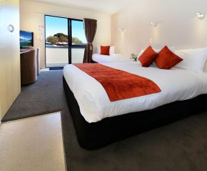 a hotel room with two beds and a balcony at Bella Vista Motel Invercargill in Invercargill