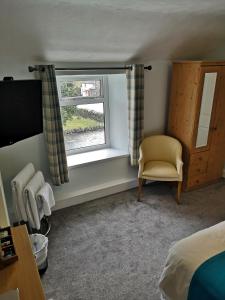 a bedroom with a bed and a window and a chair at Y Giler Arms in Pentrefoelas