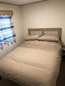 a bedroom with a white bed with a window at Celebration Tattershall with Private Hot Tub in Tattershall