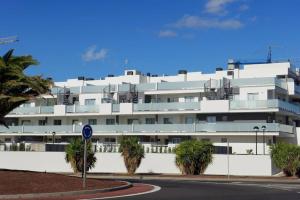 un gran edificio blanco con palmeras delante en Cosy apartment - 4 min walk from the beach - La Tejita El Medano, en La Tejita