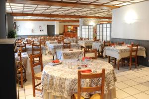 a dining room with tables and chairs with white tablecloths at Hotel Restaurant Txistulari in Itxassou