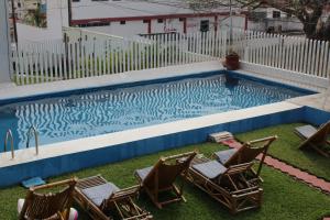 a swimming pool with three chairs and a group at Hotel Villas del Rey in Chachalacas