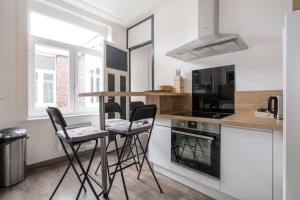 een keuken met 2 barkrukken en een aanrecht bij Cosy appartement proche Gares in Lille