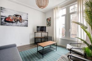een woonkamer met een bank en een tafel bij Cosy appartement proche Gares in Lille
