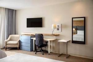 a hotel room with a desk and a bedroom at Holiday Inn & Suites - Aguascalientes by IHG in Aguascalientes