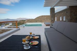 a table with plates of food and drinks on a balcony at VILLA APHRODITE- PRIVATE POOL- AMAZING AEGEAN VIEW in M&yacute;konos City