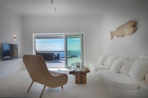 a white living room with a white couch and a television at VILLA APHRODITE- PRIVATE POOL- AMAZING AEGEAN VIEW in M&yacute;konos City