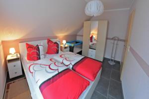 Schlafzimmer mit einem roten und weißen Bett und einem Spiegel in der Unterkunft Ferienhaus Müritzidyll / OG-Appartement in Marienfelde