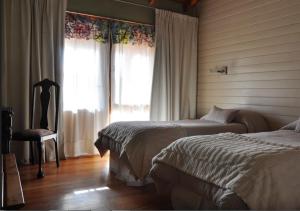 1 dormitorio con 2 camas, silla y ventana en Hosteria Ruca Kitai en Villa Lago Rivadavia
