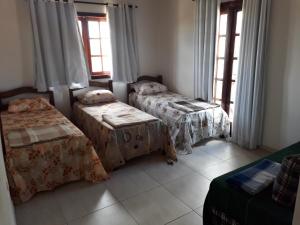 a room with three beds and a window at Casa Rústica em Gravatá in Gravatá