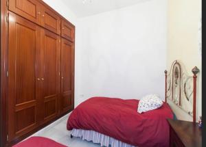 1 dormitorio con cama roja y armarios de madera en Apartamento Santa Cruz, en Sevilla