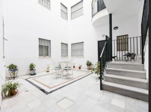 una habitación vacía con escaleras, mesas y plantas en Apartamento Santa Cruz, en Sevilla