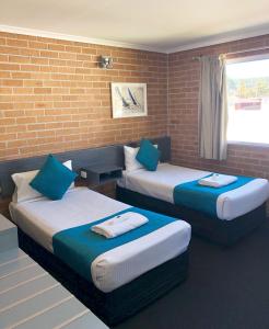 duas camas num quarto com uma parede de tijolos em The Oaks Hotel Motel em Albion Park