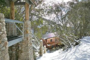 een blokhut in de sneeuw naast een gebouw bij 5 Maisonettes in Falls Creek +4 foto's