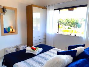 a bedroom with a bed with blue sheets and a window at Espetacular Casa 3 SUÍTES cozinha varanda vista a passos da praia in Búzios +15 photos