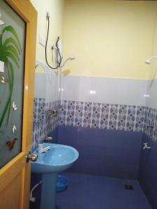een badkamer met een blauwe wastafel en een douche bij Udesh Guest in Polonnaruwa