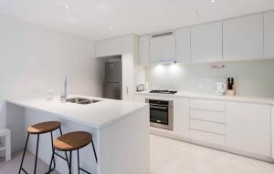 a white kitchen with two stools and a counter at Lvl 50 Skytower Fabulous Views CBD Wifi Carpark by Stylish Stays in Brisbane