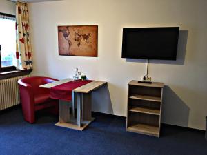 Zimmer mit einem Schreibtisch, einem TV und einem Stuhl in der Unterkunft Das Gästehaus Eimeldingen in Eimeldingen