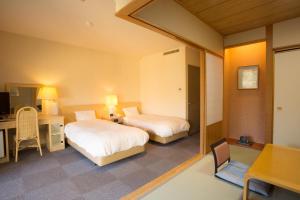 a hotel room with two beds and a desk and a table at Hotel Keipu in Hakodate