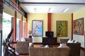 a room with chairs and a television and paintings on the walls at Hotel Tiger in Yogyakarta