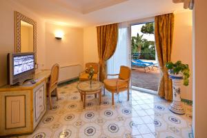 - un salon avec une télévision, une table et des chaises dans l'établissement Grand Hotel Il Moresco, à Ischia