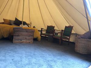 a bedroom with a bed and two chairs in a tent at Garden Beds Glamping in Blackwood