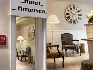 a room with chairs and a clock on the wall at Hotel America in Cannes