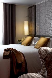 um quarto com uma cama grande e uma cadeira em Hotel America em Cannes