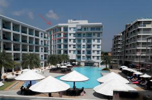 a swimming pool with white umbrellas and some buildings at Grandblue condominium 609 in Mae Pim