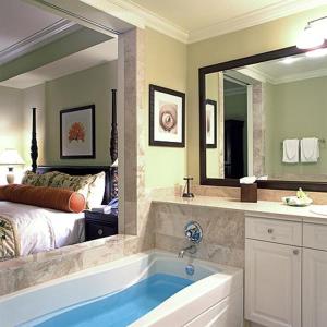 La salle de bains est pourvue d'une baignoire, d'un lit et d'un miroir. dans l'établissement VALENTINES RESORT & MARINA, à Harbour Island