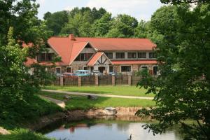 斯米尔泰内Park Hotel Brūzis的前面有池塘的房子