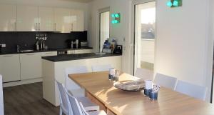 腓特烈港的住宿－BodenSEE Penthouse Friedrichshafen，厨房配有木桌和白色椅子