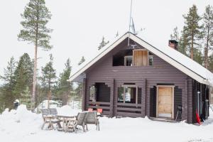 une cabine avec une table et des chaises dans la neige dans l'établissement Hillside Cottage, à Ivalo