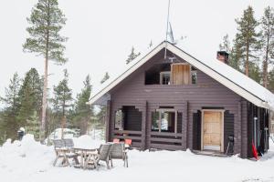 a cabin with a table and chairs in the snow at Hillside Cottage in Ivalo