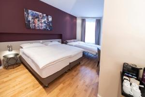 two beds in a room with purple walls and wooden floors at Sorell Hotel Rex in Zurich