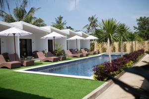 a swimming pool with lounge chairs and umbrellas at Jago Gili Air in Gili Islands
