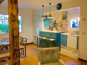 une cuisine avec des armoires bleues et une table ainsi qu'une salle à manger dans l'établissement Villa Chez Pepe, à Andernos-les-Bains