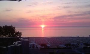 a sunset over the ocean with the sun in the sky at Hotel Grifone in Rimini