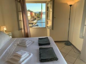a bed with two towels on it with a window at -Ortaflats- Appartamento Belvedere in Orta San Giulio