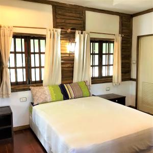 a bedroom with a large white bed with windows at Utopia House Phangan in Mae Haad