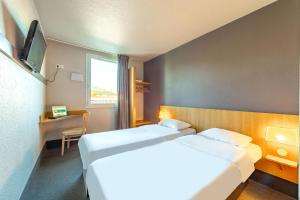 オリウルにあるB&B HOTEL Toulon Ollioulesのベッド2台とテレビが備わるホテルルームです。