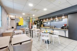 a restaurant with tables and chairs and a kitchen at B&B HOTEL Lille Centre Grand Palais in Lille